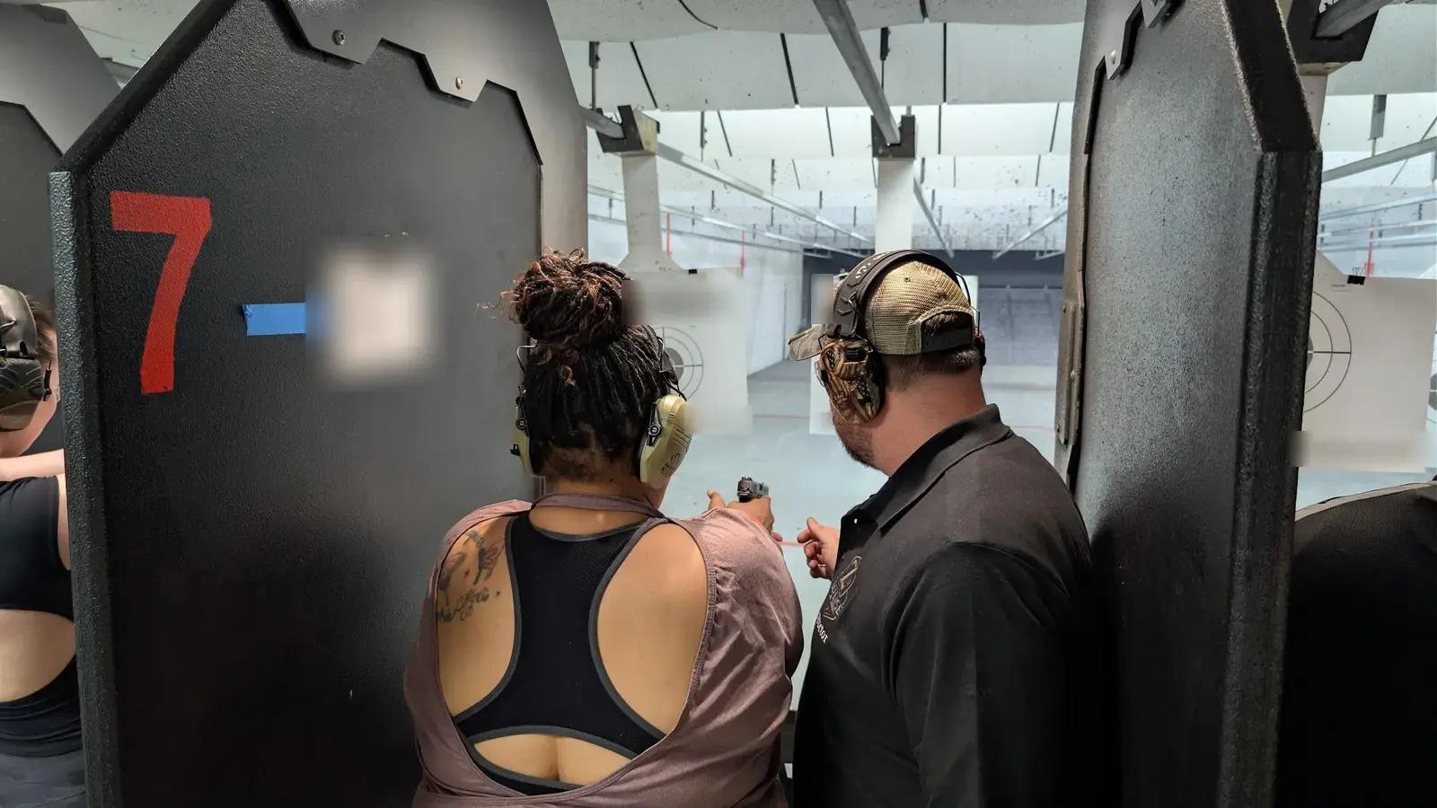 An instructor coaching a new shooter at her lane